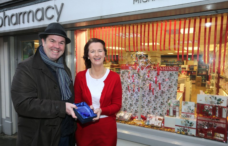 Maggie McAuley, who created the window display at Castle Pharmacy, receives the prize for taking second place in the Christmas Window Competition from Causeway Coast and Glens Borough Council Officer Shaun Kennedy.