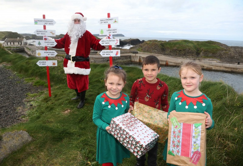 Santa Claus pictured at Ballintoy Harbour with Daisy, Charlie and Hannah from Dunseverick Primary School, as he prepares to take part in Causeway Coast and Glens Borough Council’s upcoming Christmas lights switch-on events in towns and villages across the area.
