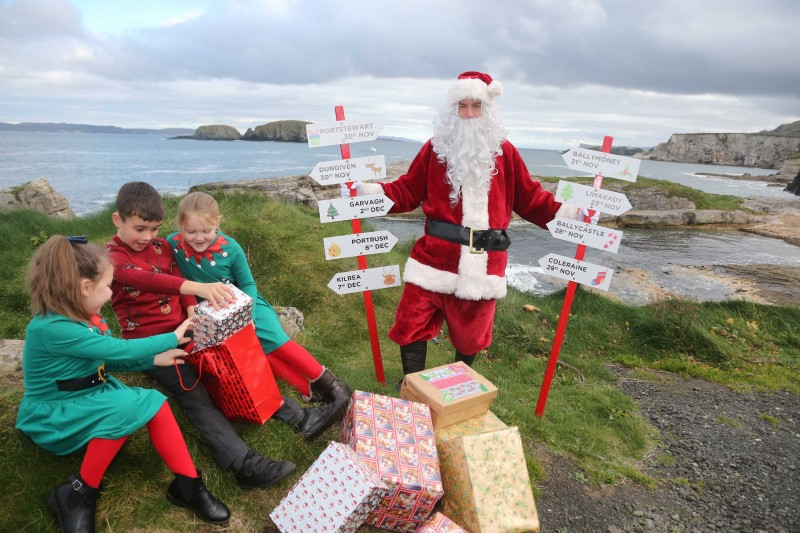 Daisy, Charlie and Hannah, Primary 4 pupils at Dunseverick Primary School, pictured with Santa Claus at Ballintoy Harbour as he prepares to take part in Causeway Coast and Glens Borough Council’s upcoming Christmas lights switch-on events in towns and villages across the area.
