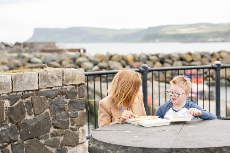 Lorcan McGonigle and mum enjoying a seafront lunch from Morton’s Fish & Chip Shop in Ballycastle, which featured in Council’s Destination Team Summer Campaign.