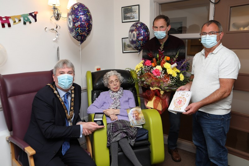 The Mayor of Causeway Coast and Glens Borough Council Councillor Richard Holmes presents a centenary coin to Katie Bamford at St James’ Lodge in Ballymoney on her 100th birthday as her sons William and James look on.