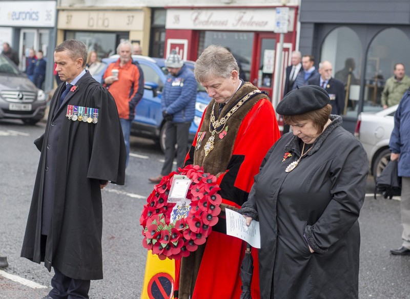 Mayor of Causeway Coast and Glens Borough Council, Alderman Mark Fielding bows his head in Remembrance alongside his wife Phyllis and Chief Executive of Causeway Coast and Glens Borough Council David Jackson, at Portstewart War Memorial on Remembrance Sunday.​