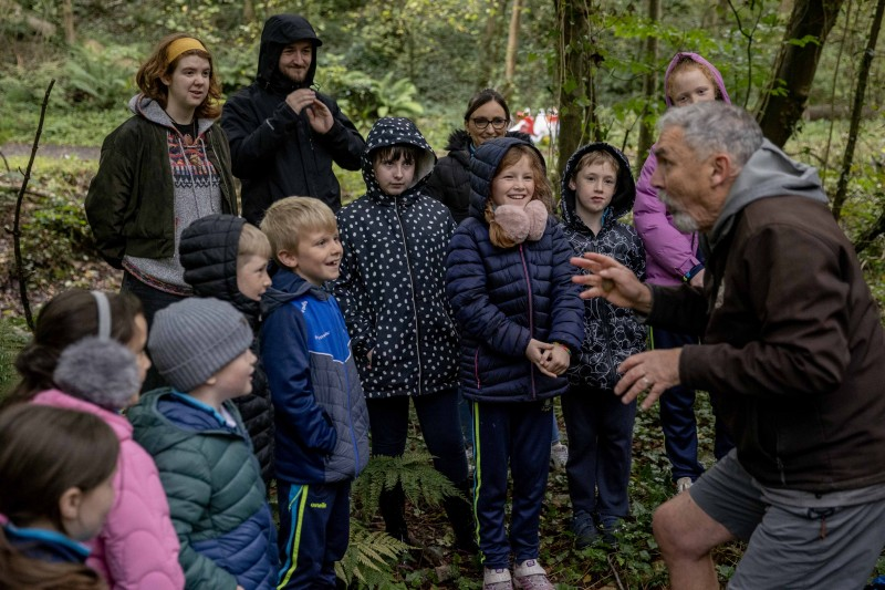 Staff and pupils from St Peter’s and St Paul’s Primary School Foreglen, with students from Ulster University School of Education, Museum Services volunteer, Rebekah Stewart, and facilitator Jim Allen preparing for hunting games in the woods.