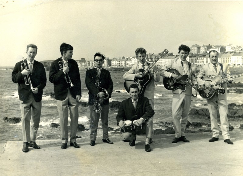 The Flingels, managed by Bobby Platt, pictured outside the Strand Ballroom in Portstewart from the 1960s, featuring Jim Quigley (trumpet), Eamon McIntyre (trumpet), Ronnie (Coalman) Ramsey (tenor sax, flute, harmonica), Trevor Keys, band leader (guitar and lead vocals), Derick O’Brien (bass guitar) and Frankie Robinson (lead guitar). Image courtesy of Trevor Keys.