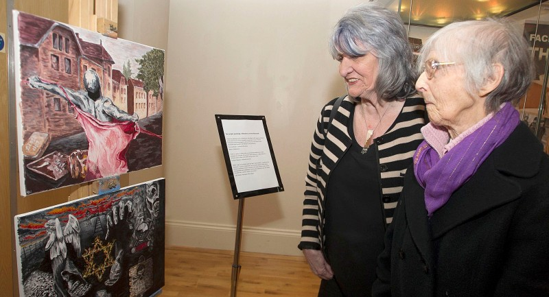 Ann Patterson and Sister Lelia Newan, look at some of the paintings depicting the Holocaust in Ballymoney Museum.