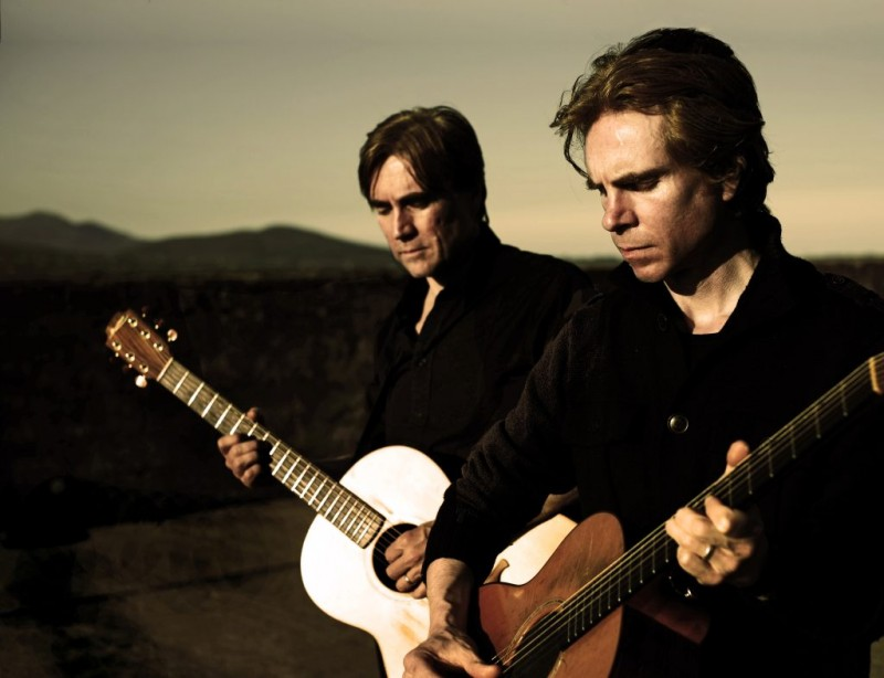 The Four Of Us – two men dressed in dark clothing playing guitars.