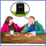 A person and person sitting at a table with a gravestone behind them