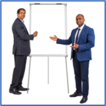 2 men in suits standing next to a white board training others