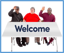 a group of smiling people at a table with a welcome sign