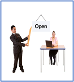 A man holding a sign which says open next to a female sitting at a desk with a laptop