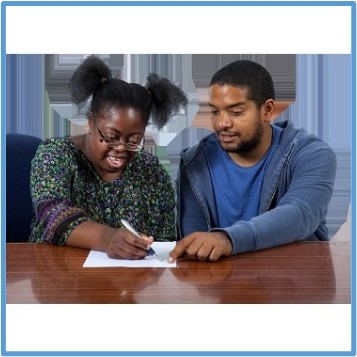 Two people sitting at a table reading and writing